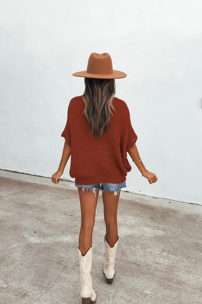 Woman in a brown hat and Cassia Boatneck Sweater - Rust pairs denim shorts with white boots, outdoors facing away from the camera.