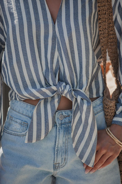 Wearing a Chambray Striped Tie Knot Shirt, light denim jeans, and carrying a woven bag.