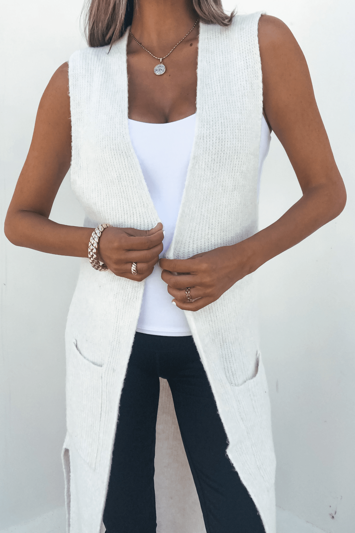 Woman in a Champagne Open Front Long Cardigan over a white top and black pants, accessorized with jewelry, on a white background.