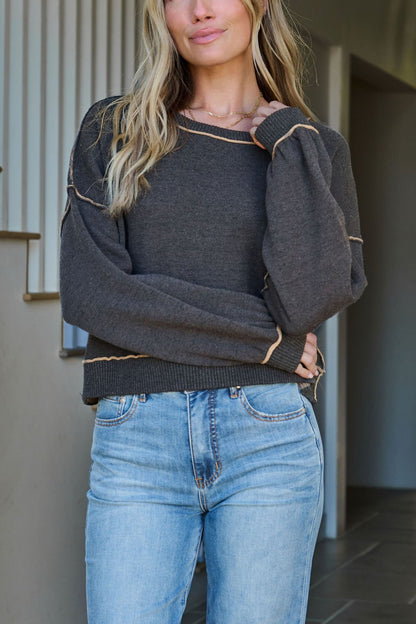 Woman indoors wearing a Charcoal Contrast Seam Detail Pullover and light blue jeans, with a staircase in the background.
