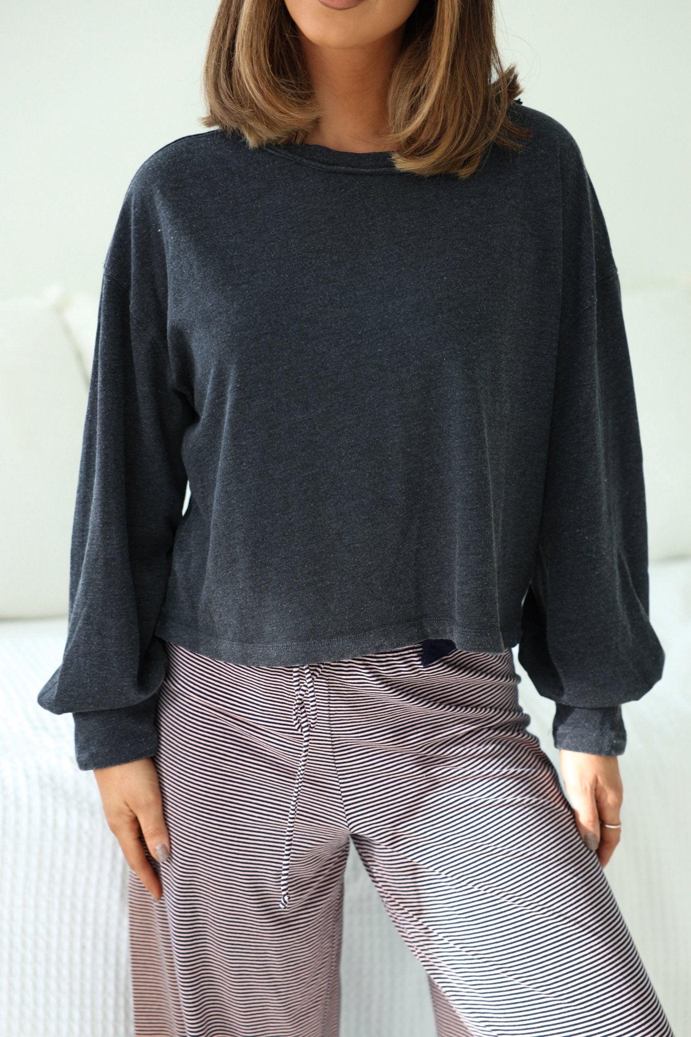 Woman in a Charcoal Mineral Wash Long Sleeve Top - FINAL SALE, standing indoors with hands by her sides.