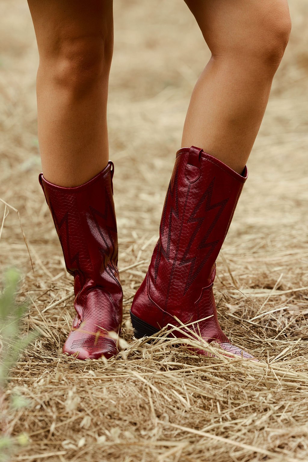 Only the bold red Chinese Laundry Josea Western Boots - FINAL SALE are visible as someone stands on dry, straw-covered ground.
