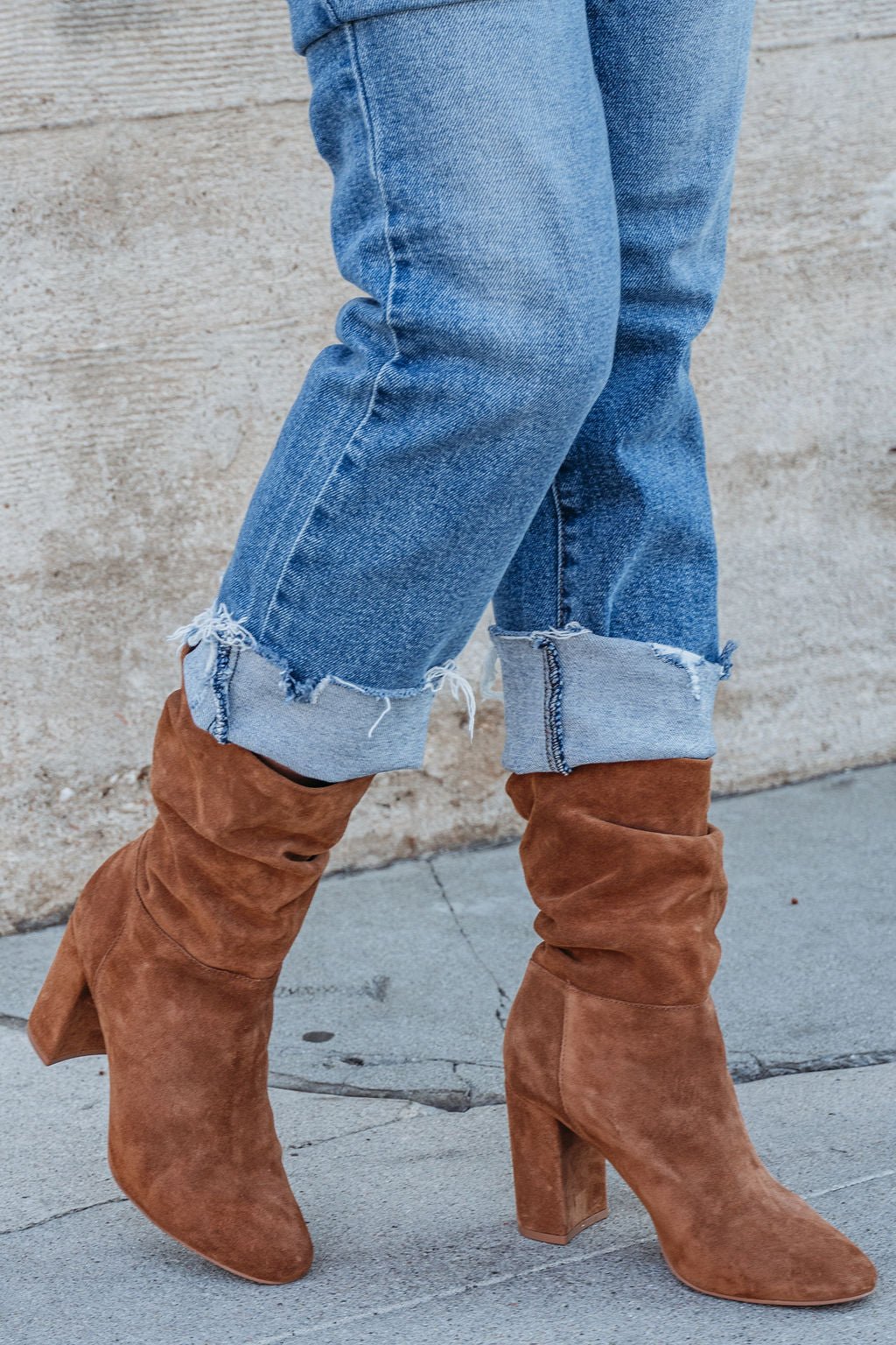 Person in cuffed blue jeans and Chinese Laundry Kipper Brown Suede Heeled Boots—a fall wardrobe essential—on a sidewalk.