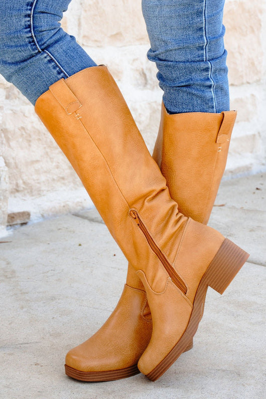 Wearing Chinese Laundry Yurie Tan Knee High Boots with a chunky heel and side zipper, paired with blue skinny jeans.