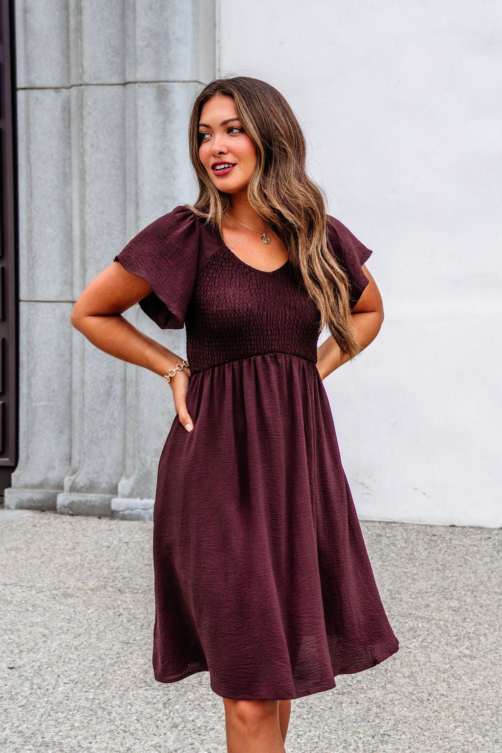 Woman outdoors in the Chocolate Brown Smocked Mini Dress - FINAL SALE, featuring a fitted bodice and relaxed skirt.