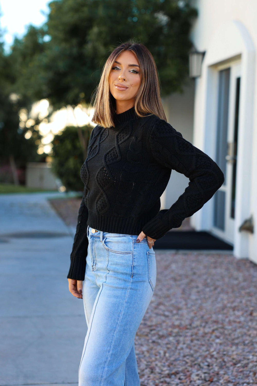 Woman with straight brown hair smiles outdoors in the Chunky Black Mock Neck Sweater - FINAL SALE and light blue jeans.