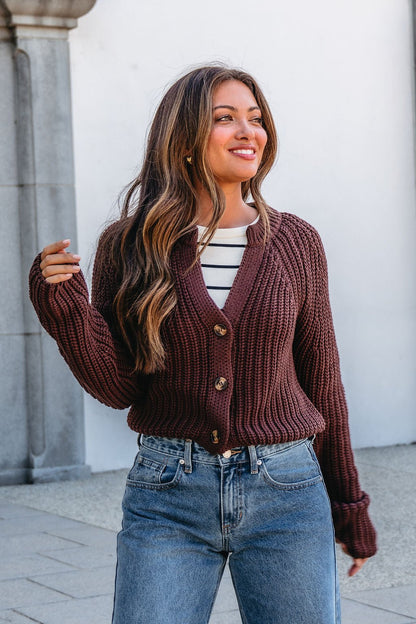 Woman wearing a Chunky Brown Button Down Cardigan over a striped shirt and blue jeans, smiling outdoors.