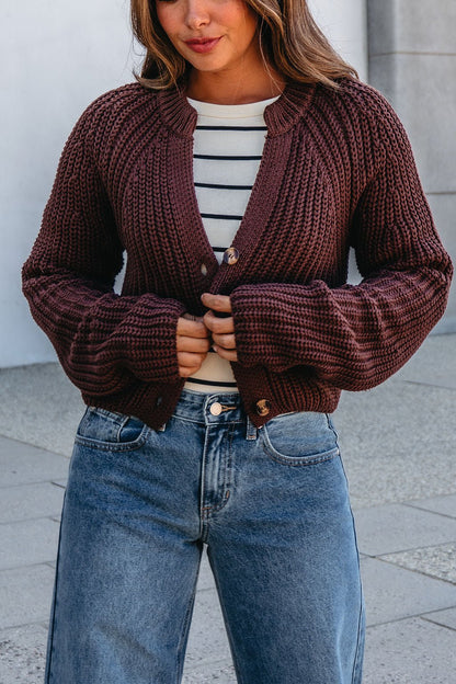 A woman wears the Chunky Brown Button Down Cardigan over a striped top and blue jeans outdoors. Magnolia Exclusive style.