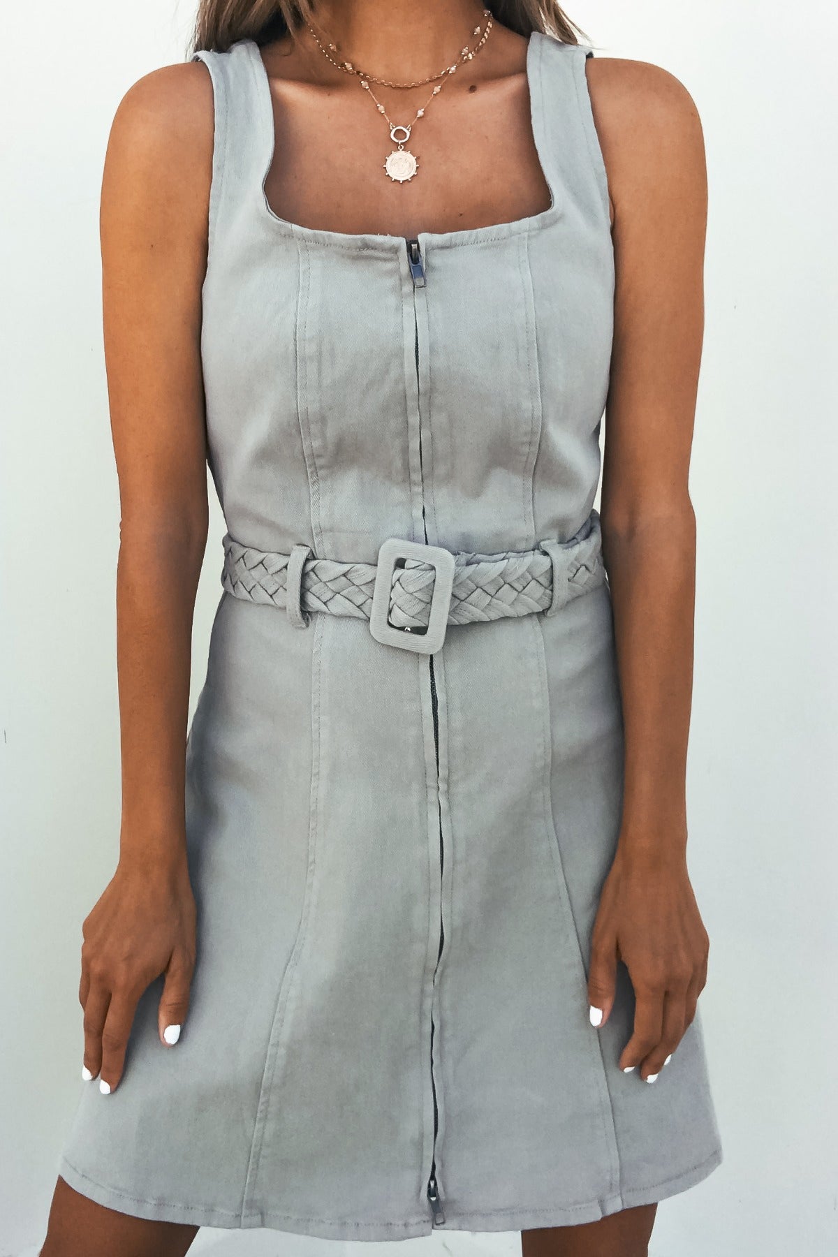 Woman wears the City Slate Belted Mini Dress, a sleeveless gray mini with square neckline and adjustable braided belt.