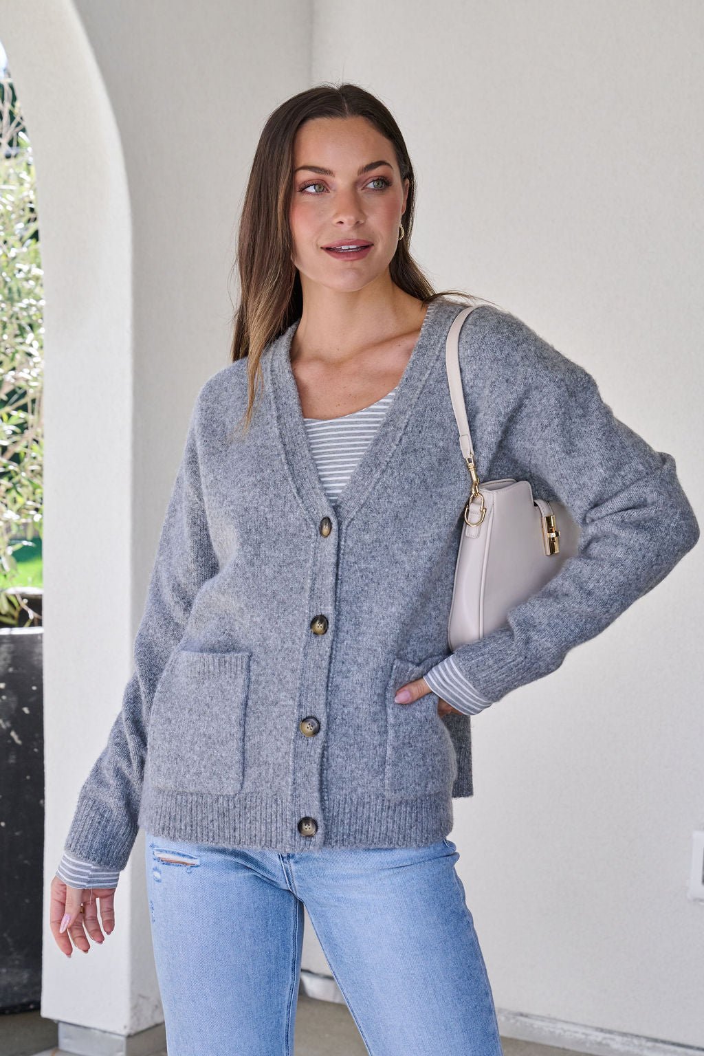 A woman wears a Cozy Grey Boyfriend Cardigan.