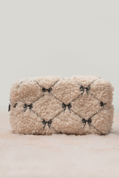The Cream Cherie Sherpa Cosmetic Pouch Bag features a black diamond pattern and bows—perfect for chic holiday gifting.