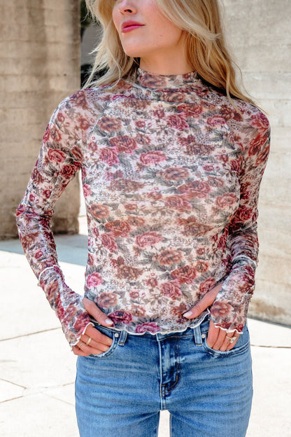 Woman in a Cream Floral Mesh Mock Neck Top - DOORBUSTER and blue jeans, standing outdoors with hands in pockets.