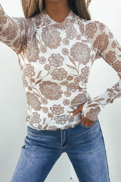 Model wears Cream Floral Mesh Top with blue jeans, posing confidently with one hand on her hip against a plain background.