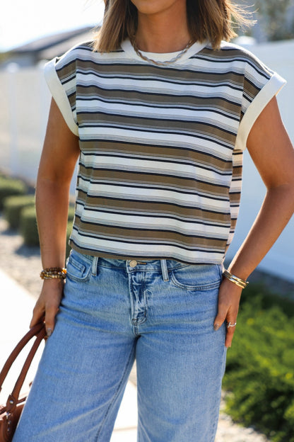 Woman wearing a Cream Multi Striped Cap Sleeve Top and light-wash jeans, standing outdoors while holding a brown bag.