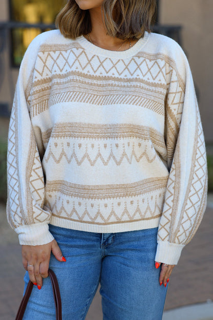Woman in a Cream Print Long Sleeve Sweater, blue jeans, and brown handbag stands outdoors.