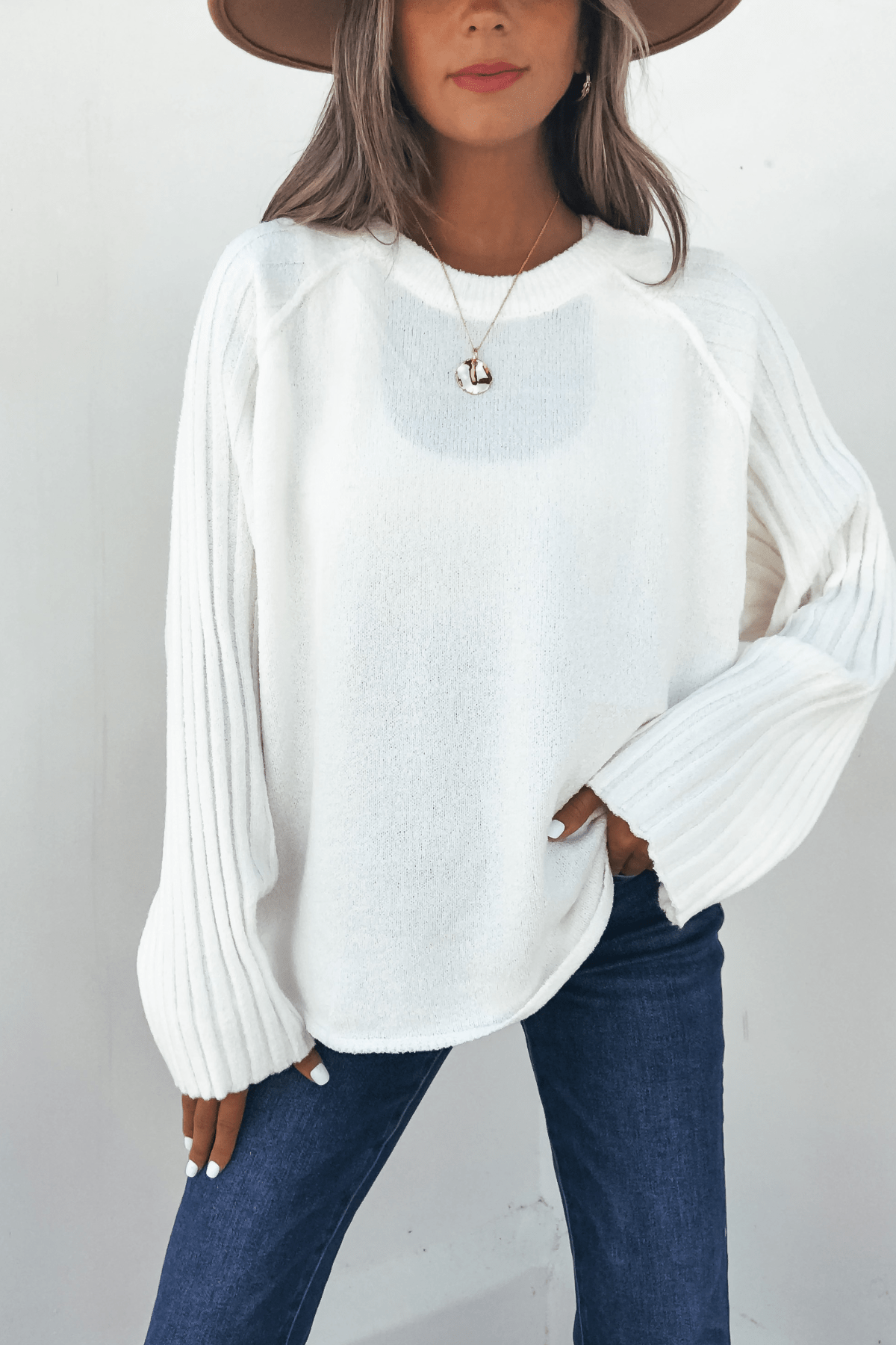 Woman in a wide-brim hat wears the Cream Raglan Sleeve Textured Sweater and blue jeans, standing against a white background.