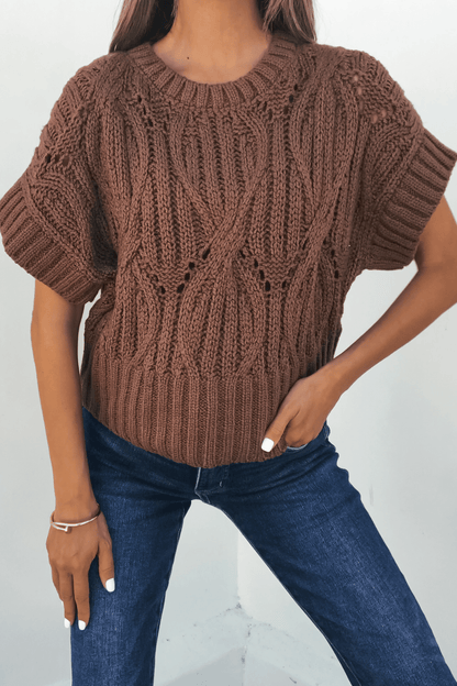 Woman in a Dark Brown Crochet Knit Sweater and blue jeans, posing with one hand on her hip—classic autumn style.