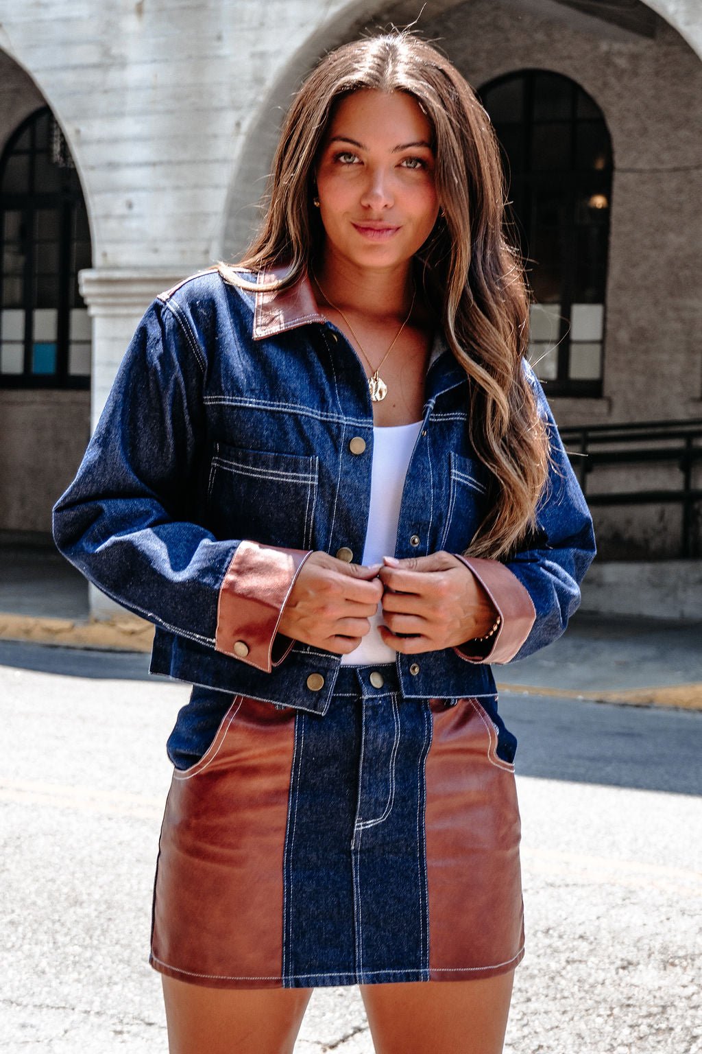 Woman outdoors in a Dark Denim Contrast Button Up Jacket - DOORBUSTER, paired with a matching skirt and white top.