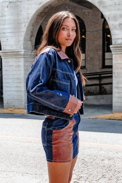 A woman poses outdoors by a stone archway in the Dark Denim Contrast Button Up Jacket - DOORBUSTER.