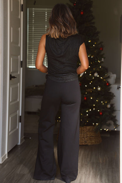 A woman stands indoors near a decorated Christmas tree, wearing Elan Black Seam Detail Wide Leg Pull-On Pants.