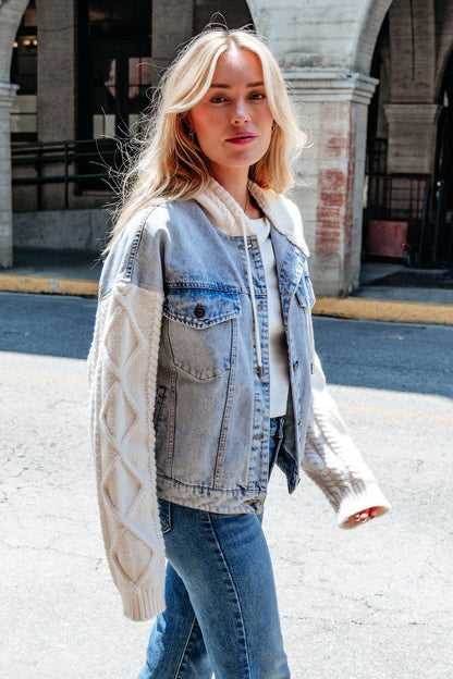 A woman enjoys the sun in an Elan Denim Hooded Sweater Jacket with cable knit sleeves—a stylish transitional layer.