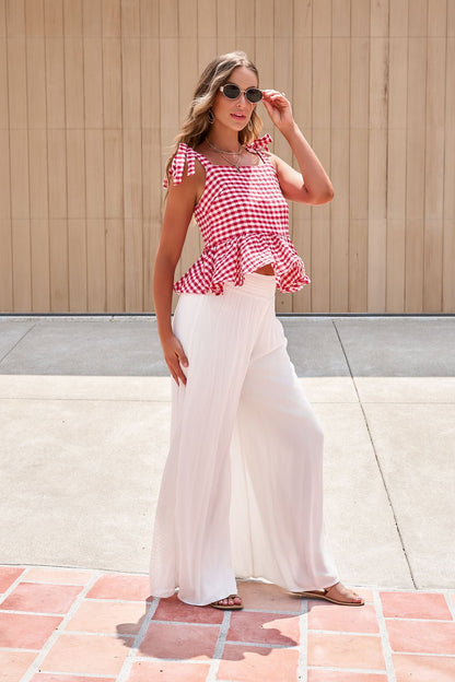 Woman wears sunglasses, a red gingham ruffle top, and Elan Flowy Wide Leg Pants - Ivory outdoors on a sunny day.
