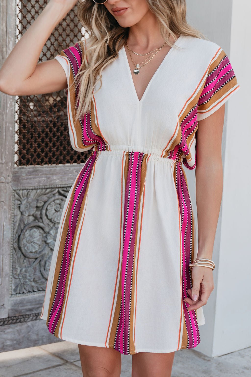 Woman in the ELAN Natural Striped Kimono Dress with elastic waist, outdoors by a decorative door—ideal for resort wear style.