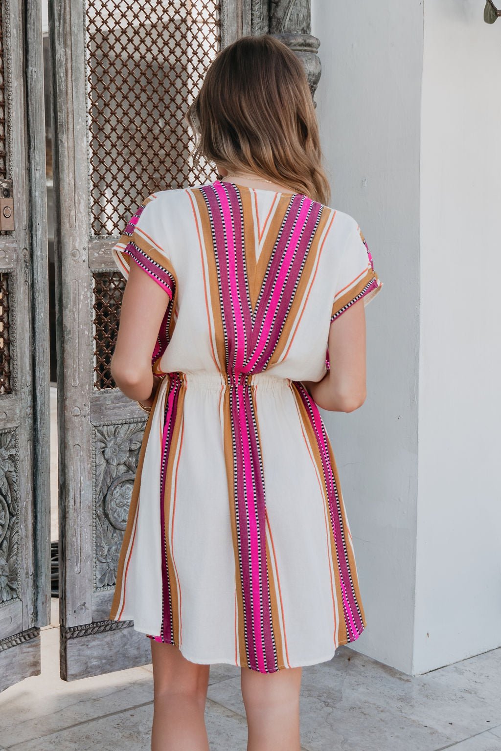 Woman with wavy hair wears the ELAN Natural Striped Kimono Dress—pink and orange stripes, perfect for resort wear.