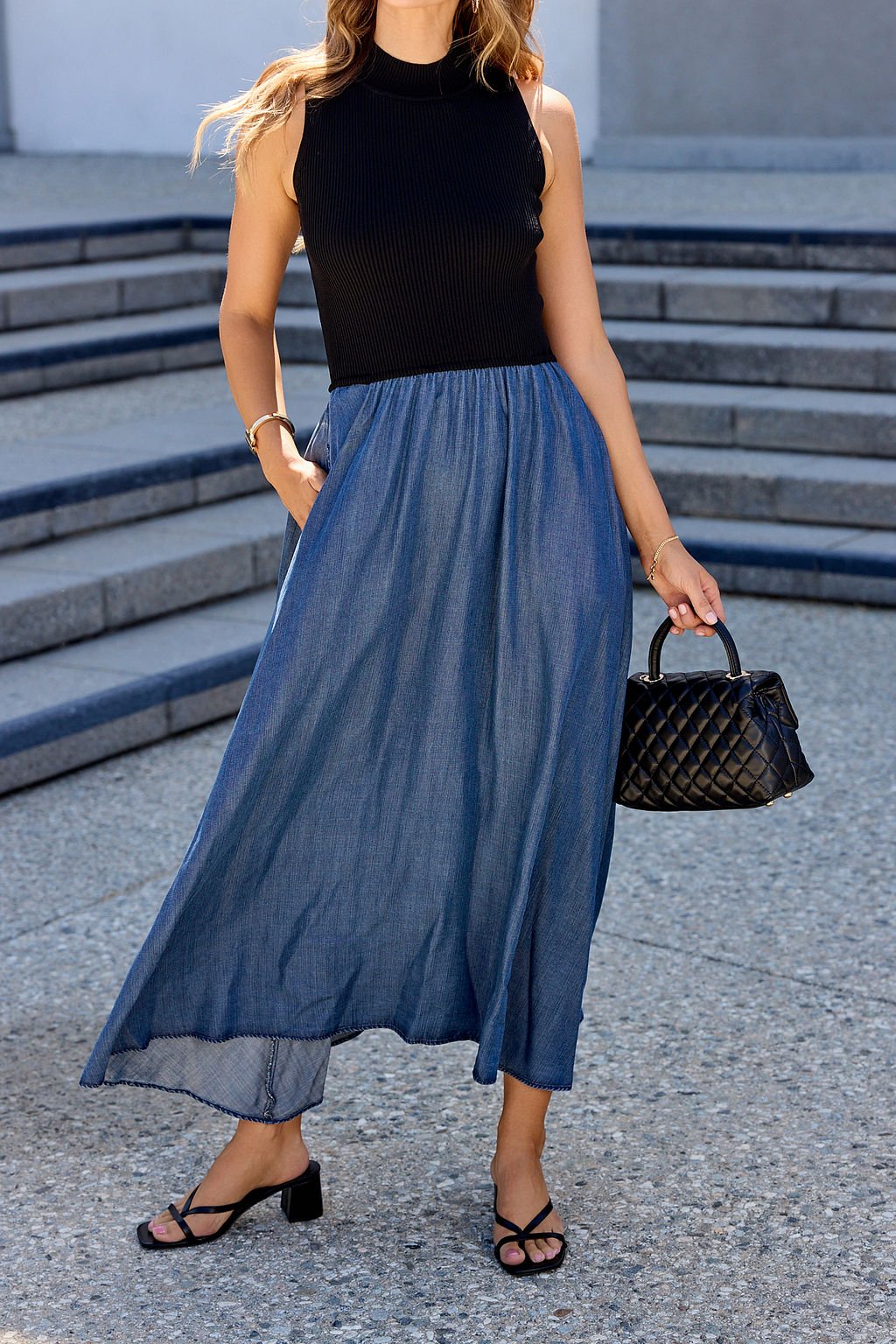 Woman outdoors in the Elan Two Tone Midi Dress - Navy, sandals, and a quilted black handbag.