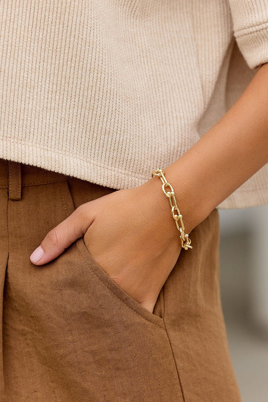 A person wears the Elegant Gold Chain Link Bracelet with tan pants and a beige top, their hand resting in a pocket.