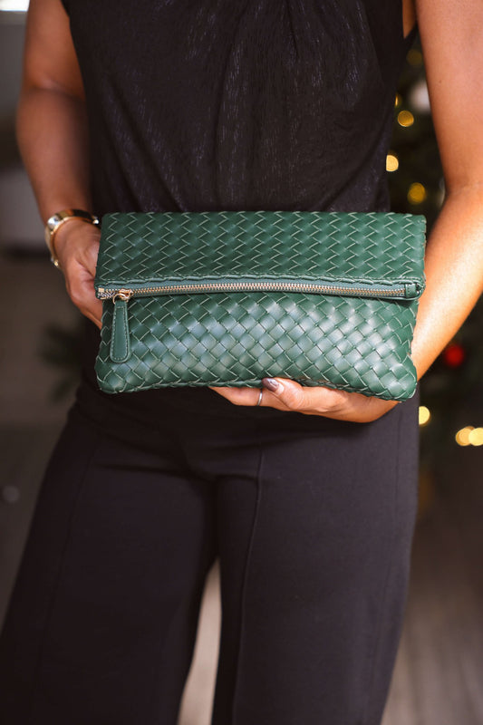 Person holding an Emerald Grace Vegan Leather Clutch with a zipper, paired with a black outfit.