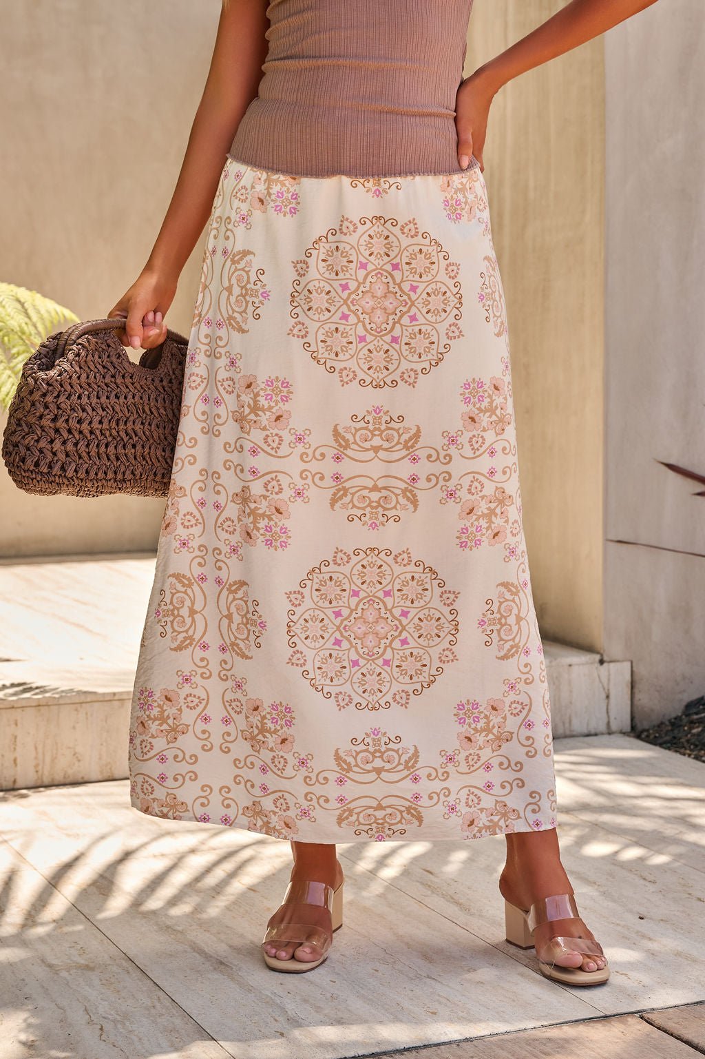 Woman in the Evelyn Cream Print Maxi Skirt, featuring pink and gold bandana-inspired patterns and a flowing full-length silhouette.