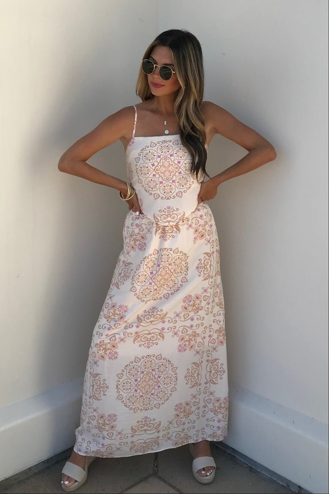 Woman in Evelyn Cream Print Tank Top and sunglasses stands against a white wall, hands on hips.