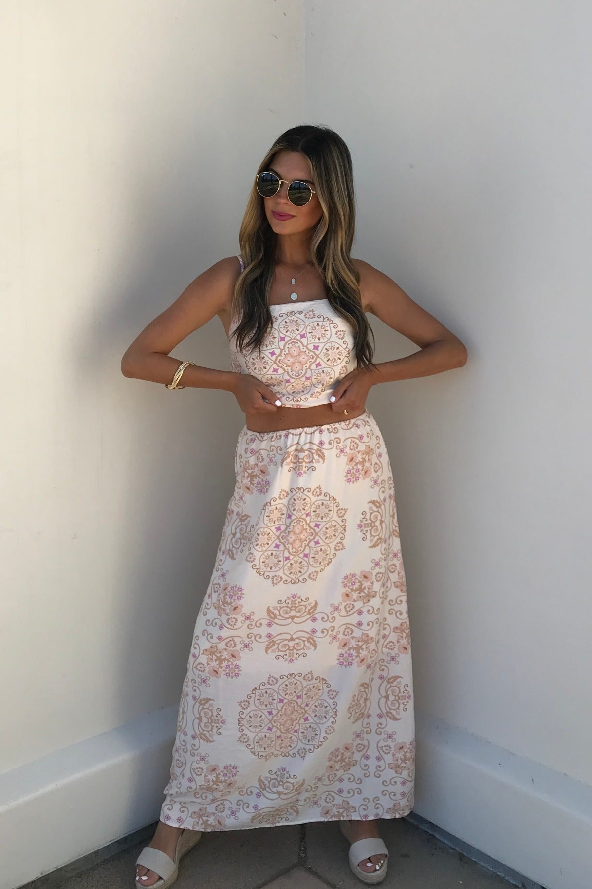 Woman in sunglasses and an Evelyn Cream Print Tank Top stands against a white wall, hands at her waist, smiling slightly.