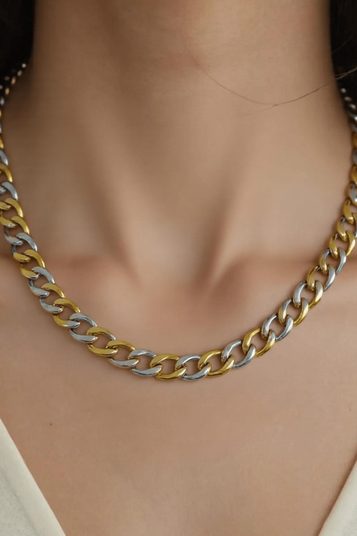 A person wearing the Farrah B Gold Plated Mixed Metal Chain Necklace with a V-neck cream top.