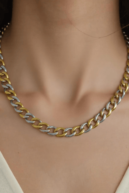 A person wearing the Farrah B Gold Plated Mixed Metal Chain Necklace with a V-neck cream top.