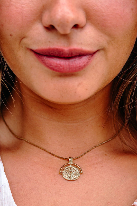 A woman wears the Farrah B When In Rome Gold Coin Pendant Necklace, smiling softly with natural makeup.