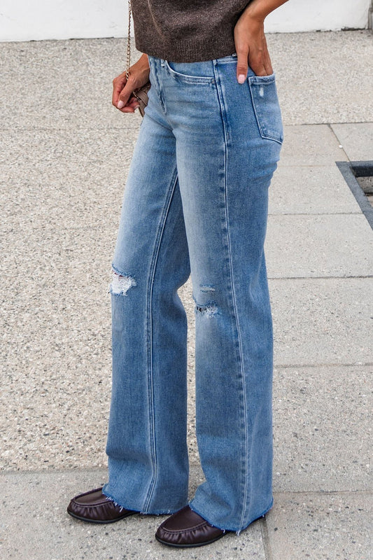 Person in Flying Monkey Distressed Wide Leg Jeans - Light Wash, brown top, and flats stands on textured pavement.