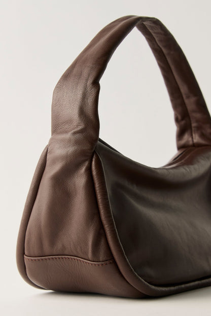 A dark brown FREE PEOPLE ESPRESSO ALEXA SHOULDER BAG with a curved, integrated handle.