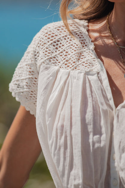 Close-up of a woman outdoors in sunlight wearing the Free People Ivory Gemma Embroidered Top with scalloped lace details.