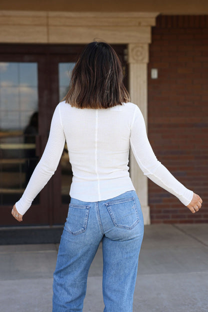 A woman in a white shirt layered with the Free People Ivory Going Places Cardigan.