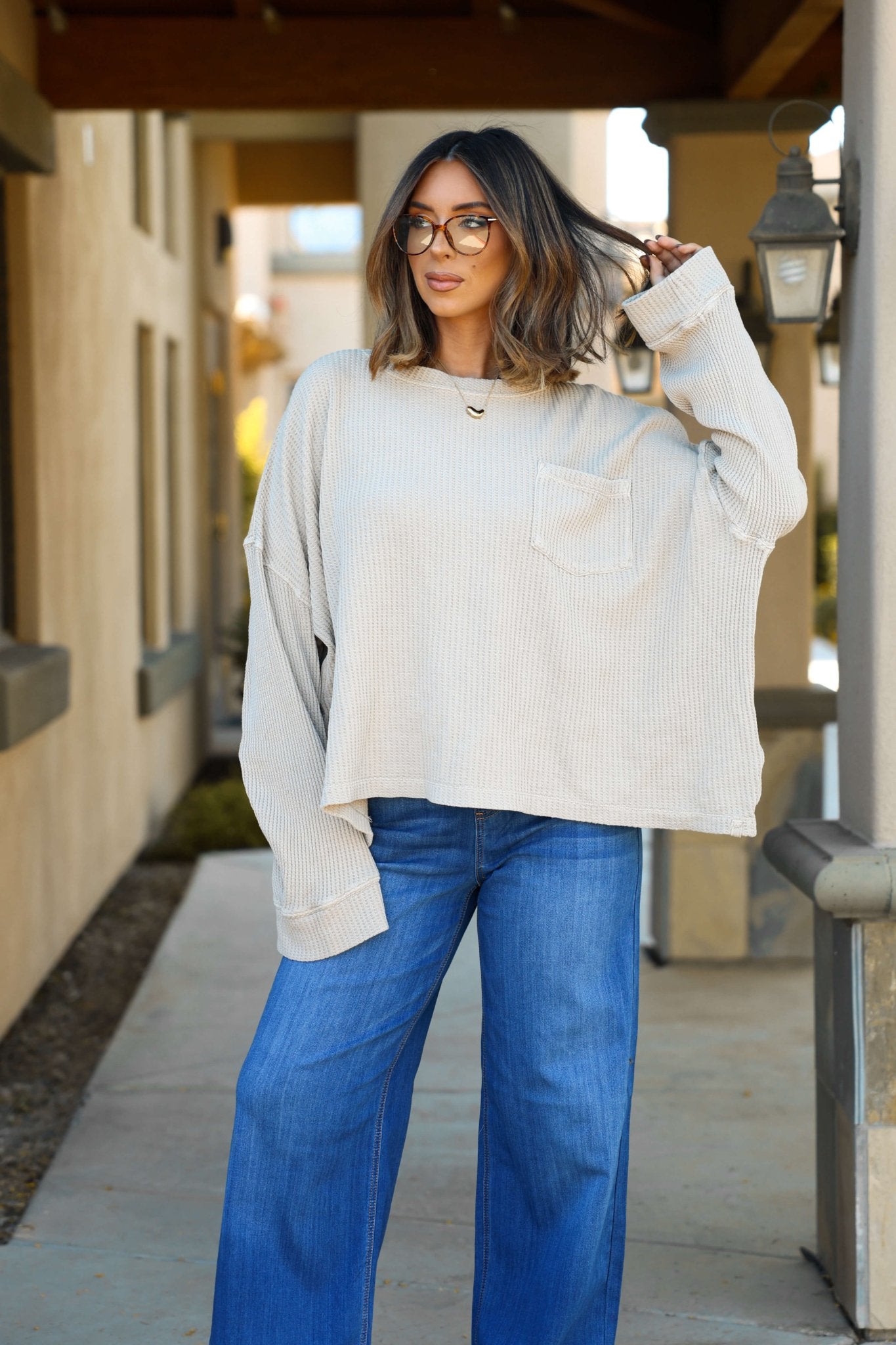 Woman with shoulder-length hair in glasses wears a Free People Stone Dawson Pocket Thermal Top, standing outdoors on a pathway.
