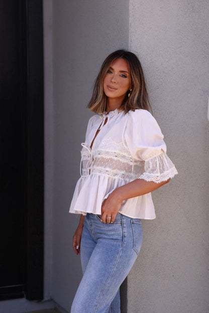 Woman with shoulder-length hair wears the Free People White Forever Young Top - FINAL SALE, standing by a light wall, facing the camera.