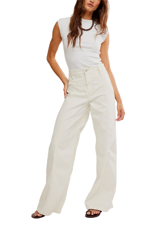 Woman in sleeveless white top, Free People White Libre Wide Leg Jeans, black sandals, and beaded necklace on a white background.