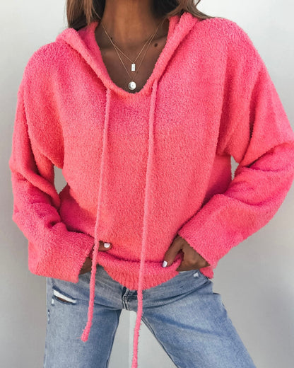 Woman wearing a Fuzzy Pink Hooded Sweater, light blue ripped jeans, and layered necklaces.