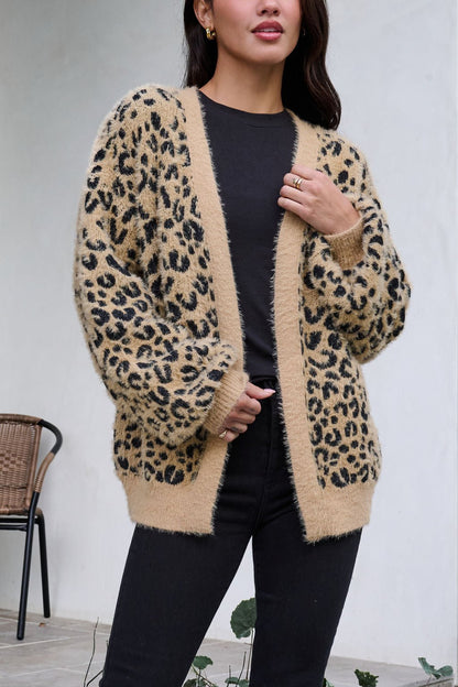 A woman wears a Fuzzy Tan Leopard Open Front Cardigan over a black shirt and pants.