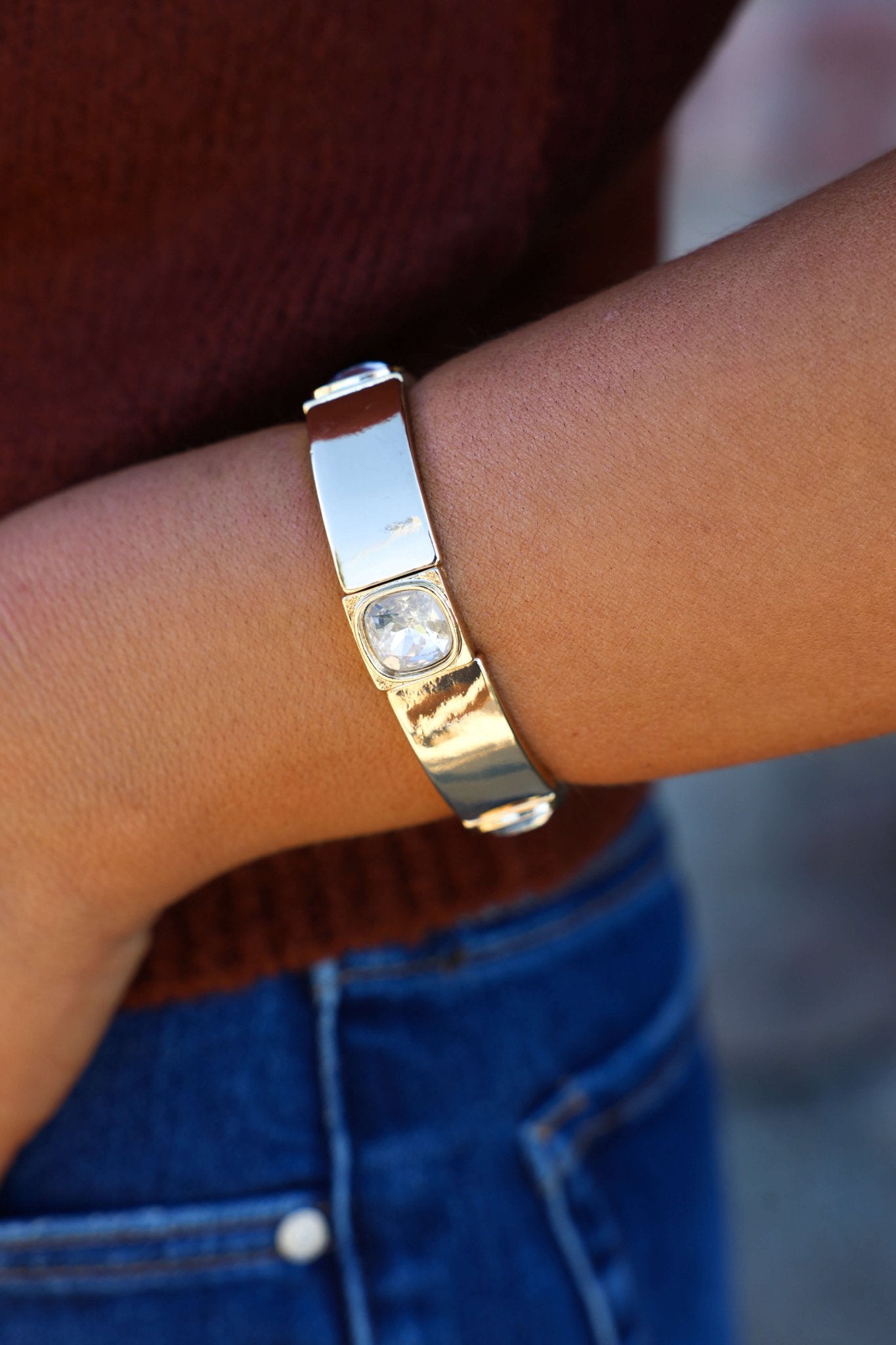 Someone styles the Gold Center Gemstone Bracelet with blue jeans and a maroon top for a chic, sparkling look.