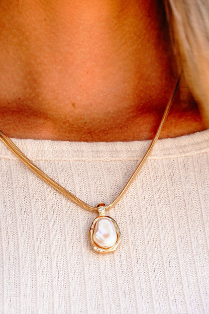 A Gold Chain Pearl Pendant Necklace is styled over a cream ribbed top in this close-up.