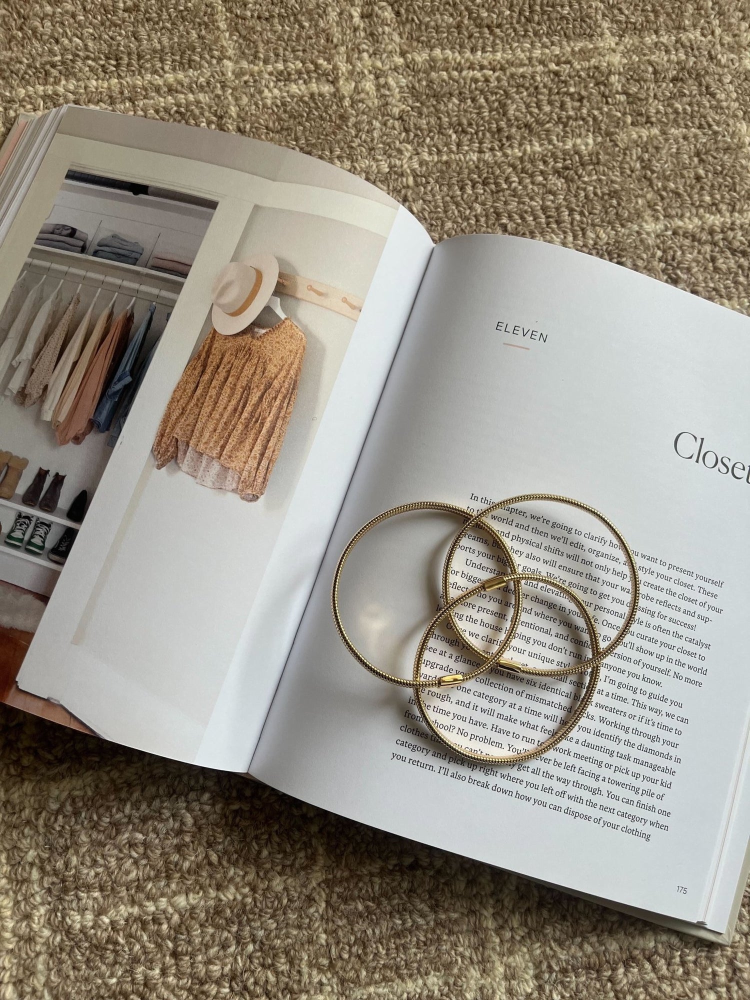An open book with a closet photo and text displays the Gold Coiled Metallic Bracelet Set atop a beige textured surface.