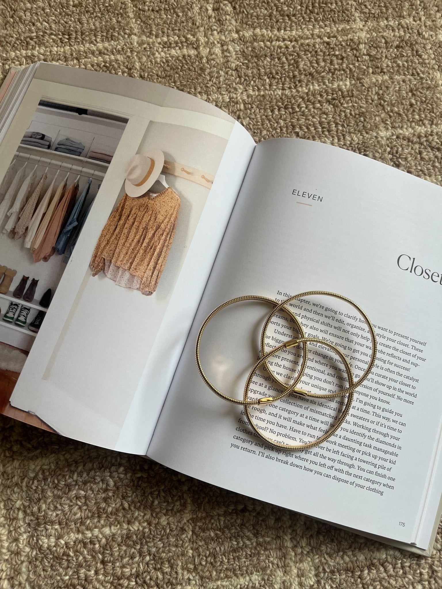 An open book with a closet photo and text displays the Gold Coiled Metallic Bracelet Set atop a beige textured surface.